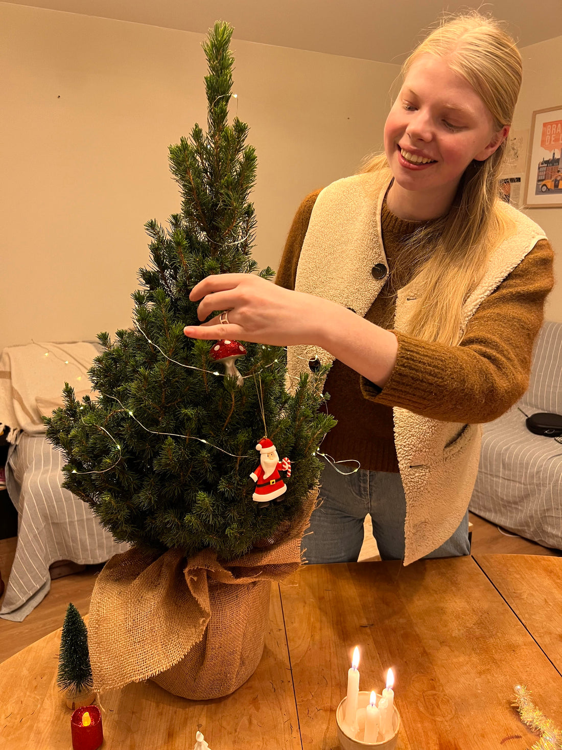 Petit sapin de Noël en pot décoré, posé sur une table dans un salon minimaliste